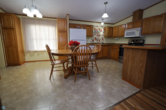 kitchen with hanging light fixtures, white appliances, a notable chandelier, crown molding, and vaulted ceiling