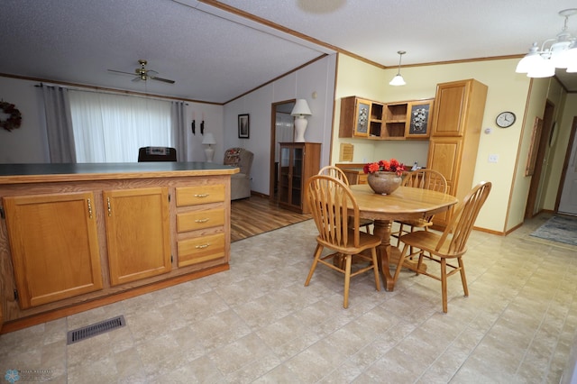 dining space featuring ceiling fan, crown molding, and a textured ceiling