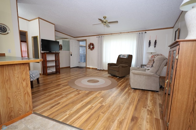 living room featuring ornamental molding, light hardwood / wood-style floors, ceiling fan, and a textured ceiling