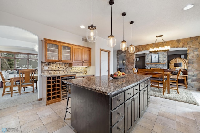 kitchen featuring a breakfast bar area, tasteful backsplash, beverage cooler, a kitchen island, and light carpet