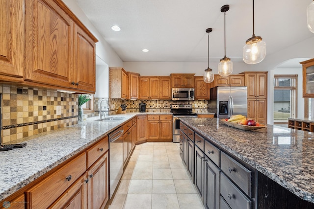 kitchen featuring appliances with stainless steel finishes, tasteful backsplash, hanging light fixtures, a wealth of natural light, and light stone countertops