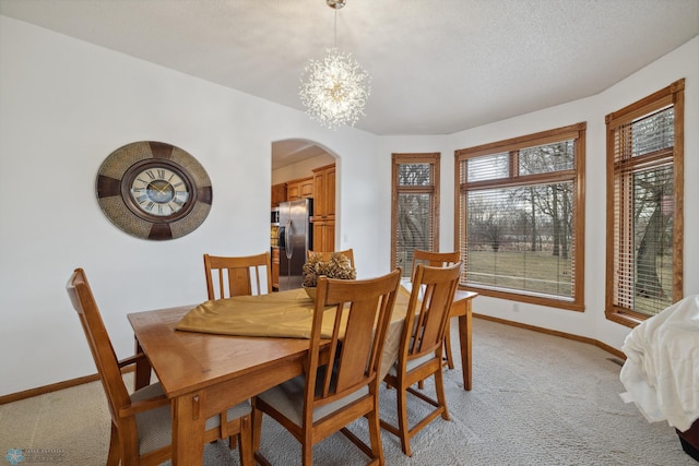 carpeted dining area featuring an inviting chandelier and a textured ceiling