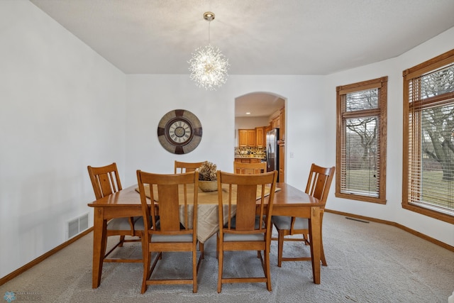 dining space featuring plenty of natural light, a notable chandelier, and light colored carpet