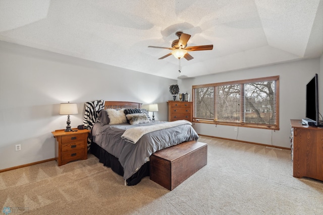 carpeted bedroom featuring a textured ceiling, a raised ceiling, and ceiling fan