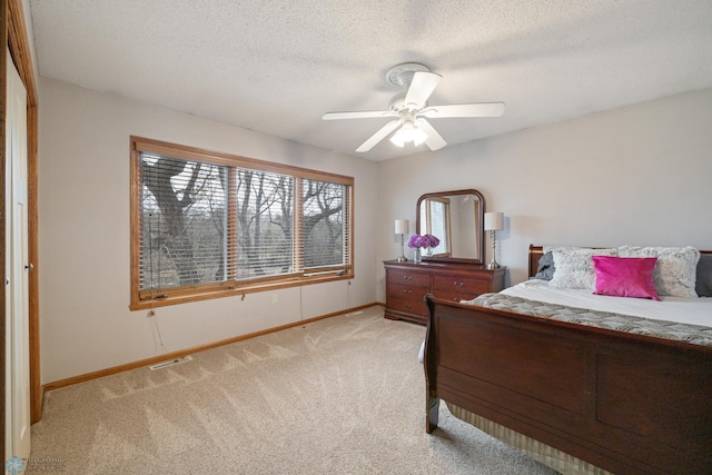 bedroom featuring a textured ceiling, light colored carpet, and ceiling fan