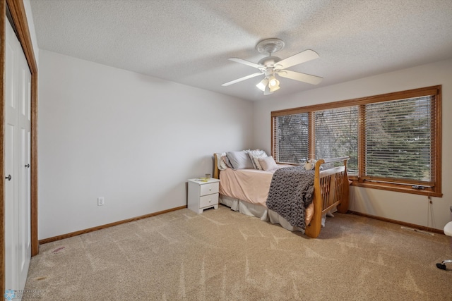 carpeted bedroom with a textured ceiling, ceiling fan, and a closet