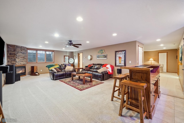 carpeted living room featuring a stone fireplace, a wood stove, and ceiling fan