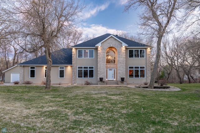 colonial-style house featuring a garage and a front lawn