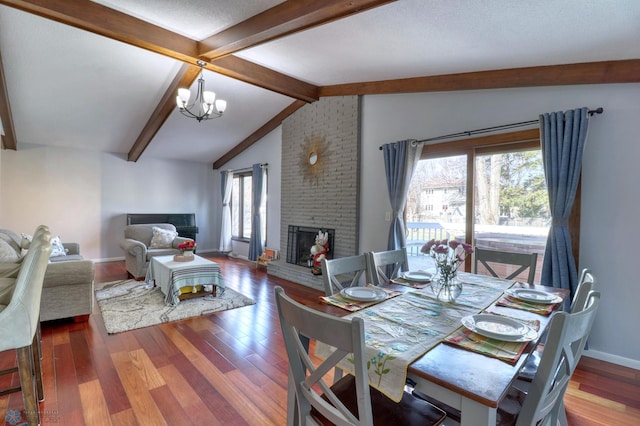 dining room with lofted ceiling with beams, a notable chandelier, wood-type flooring, a fireplace, and brick wall