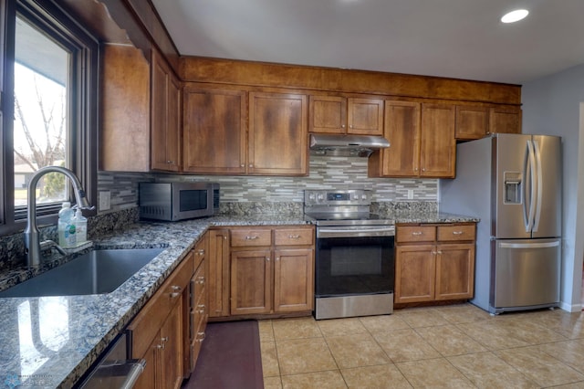 kitchen featuring stainless steel appliances, light stone countertops, backsplash, sink, and light tile patterned flooring