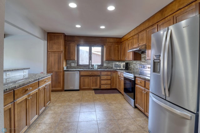 kitchen with stainless steel appliances, backsplash, sink, dark stone counters, and light tile patterned flooring