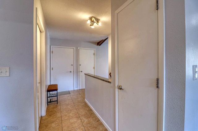 hallway featuring a textured ceiling and light tile patterned floors