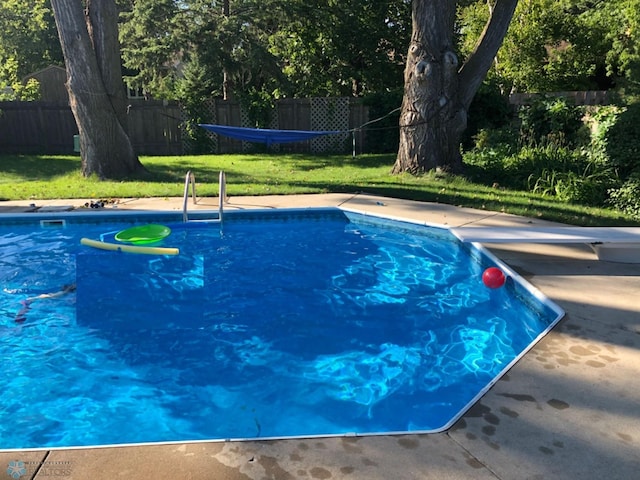 view of swimming pool with a yard and a diving board