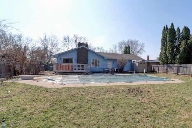 rear view of property featuring a lawn, a swimming pool side deck, and an outdoor structure