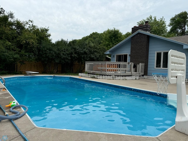 view of swimming pool with a diving board and a wooden deck