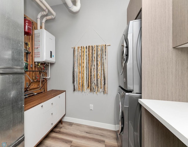 laundry room with light hardwood / wood-style floors, water heater, and stacked washing maching and dryer