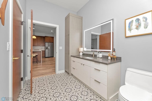 bathroom featuring tasteful backsplash, toilet, tile floors, and vanity