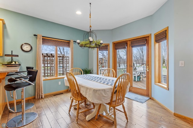 dining area with a notable chandelier, a wealth of natural light, and light hardwood / wood-style flooring