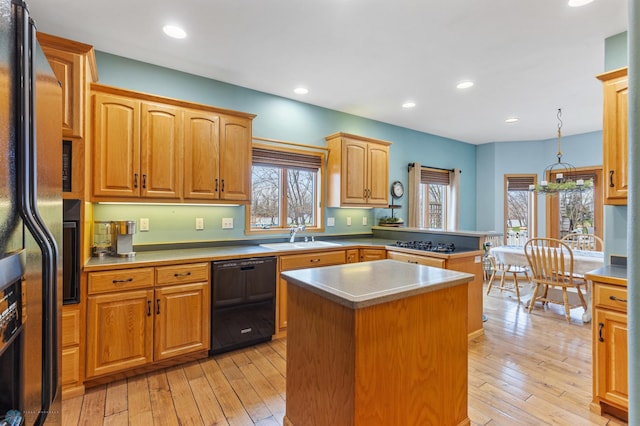 kitchen featuring pendant lighting, plenty of natural light, black dishwasher, and light wood-type flooring