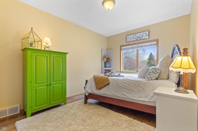 bedroom with ornamental molding and dark wood-type flooring