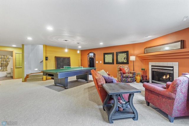 recreation room with light carpet and a tiled fireplace