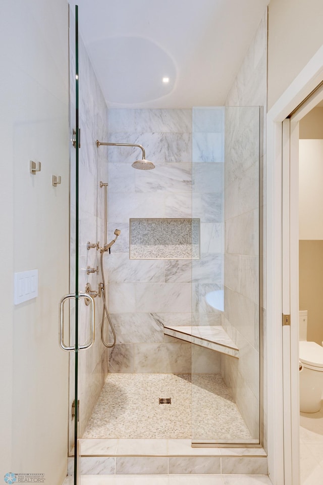 bathroom featuring a shower with door and toilet