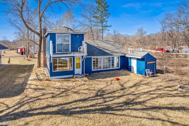 rear view of property featuring a balcony and a lawn