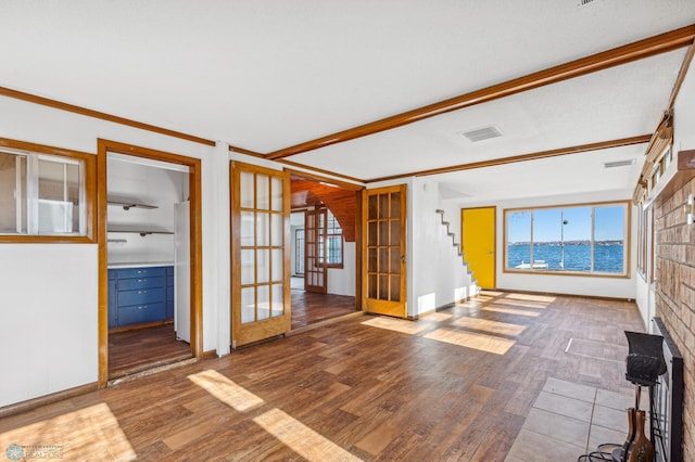 unfurnished living room with ornamental molding, french doors, a water view, and hardwood / wood-style flooring