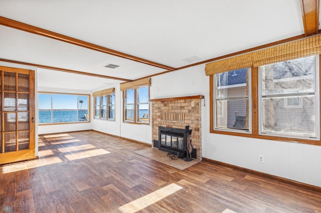 unfurnished living room with hardwood / wood-style flooring, a wood stove, a fireplace, and a water view