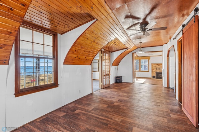 bonus room featuring dark wood-type flooring, a healthy amount of sunlight, a barn door, and wood ceiling