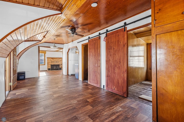 bonus room featuring wood ceiling, dark hardwood / wood-style floors, ceiling fan, and a barn door