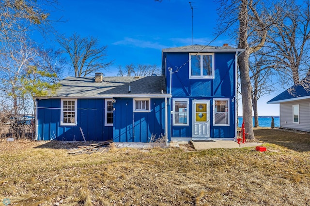 rear view of house with a yard and a water view