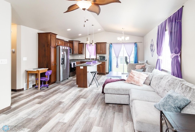 living room featuring ceiling fan with notable chandelier, vaulted ceiling, light hardwood / wood-style flooring, and sink