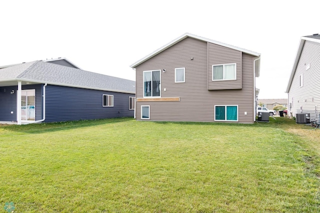 rear view of house featuring central AC unit and a lawn