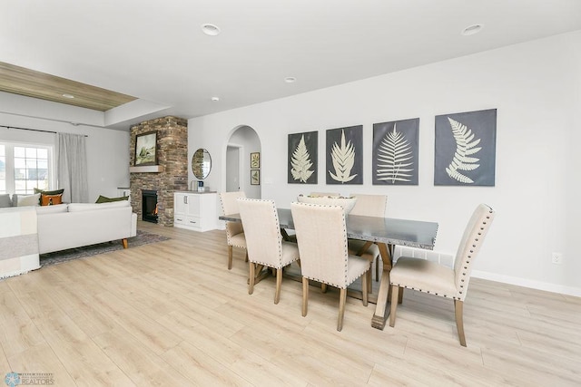 dining room featuring light wood-type flooring and a stone fireplace