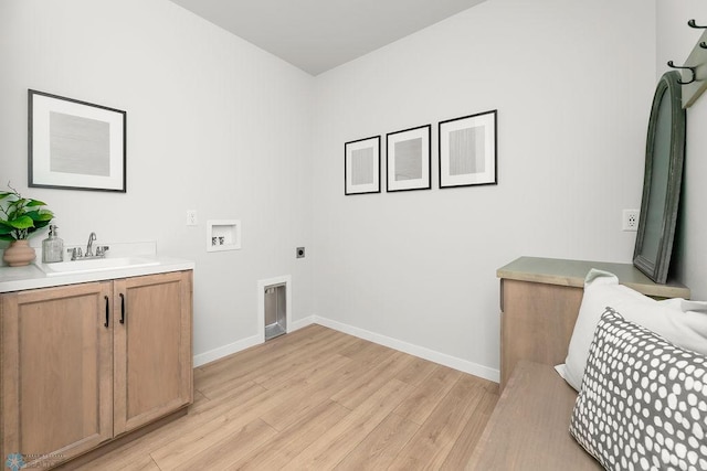 laundry area featuring light wood-type flooring, hookup for an electric dryer, washer hookup, sink, and cabinets