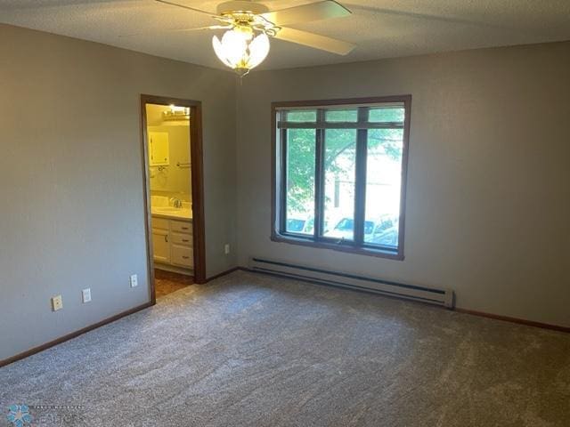 unfurnished bedroom featuring ensuite bath, ceiling fan, dark carpet, and baseboard heating