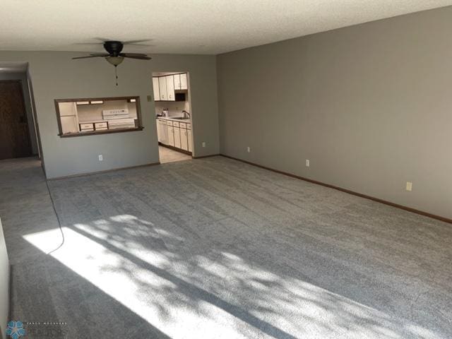 spare room featuring light carpet, sink, and ceiling fan