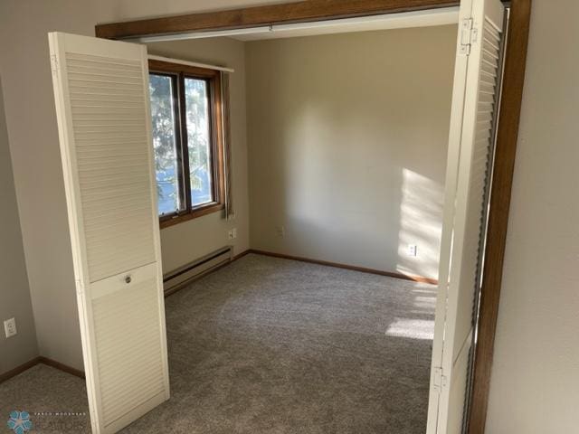 carpeted spare room featuring baseboard heating