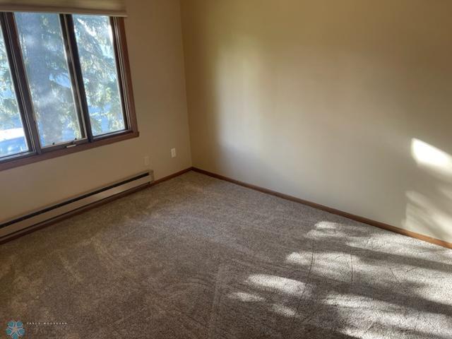 spare room with a wealth of natural light, carpet, and a baseboard heating unit