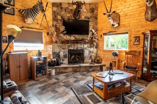 tiled living room featuring wood walls and a stone fireplace