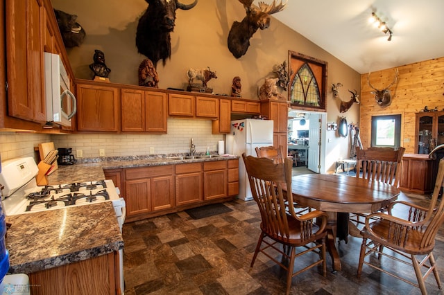 tiled dining room featuring high vaulted ceiling, sink, and track lighting