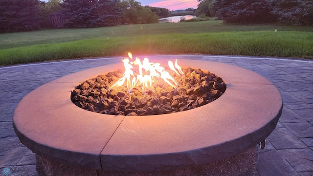 patio terrace at dusk featuring a fire pit and a yard