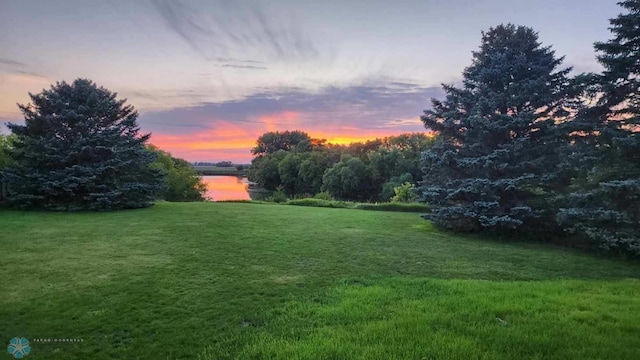 yard at dusk featuring a water view