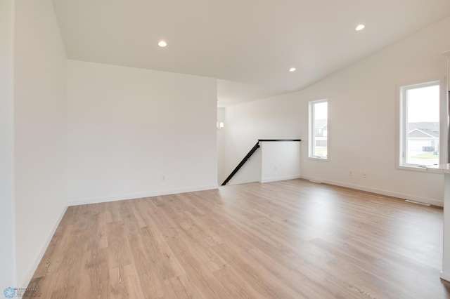 empty room with light hardwood / wood-style flooring and vaulted ceiling