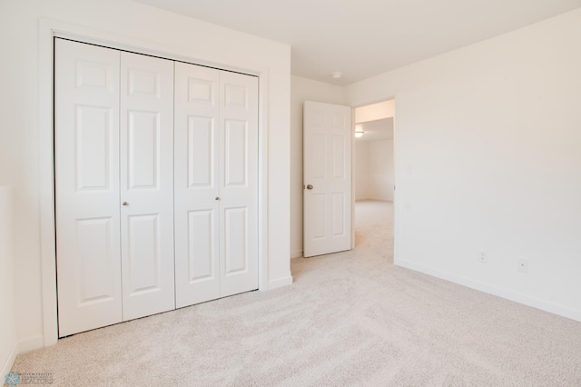 unfurnished bedroom with light carpet and a closet