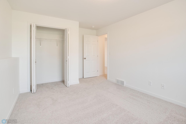 unfurnished bedroom featuring light carpet and a closet