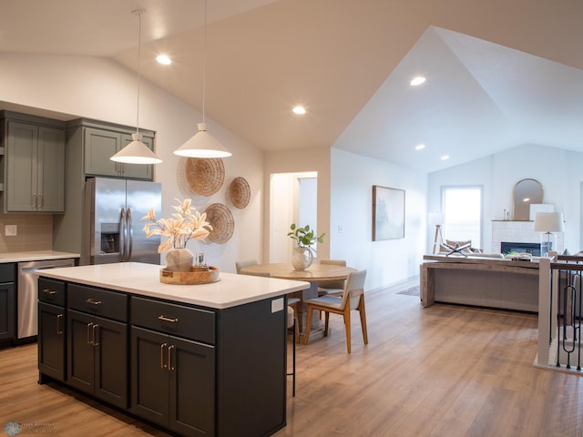 kitchen with lofted ceiling, backsplash, light hardwood / wood-style floors, appliances with stainless steel finishes, and a tiled fireplace