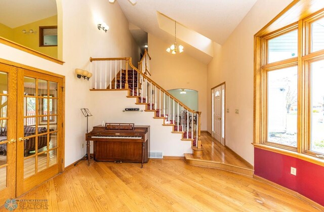 foyer entrance featuring high vaulted ceiling, light hardwood / wood-style flooring, and french doors