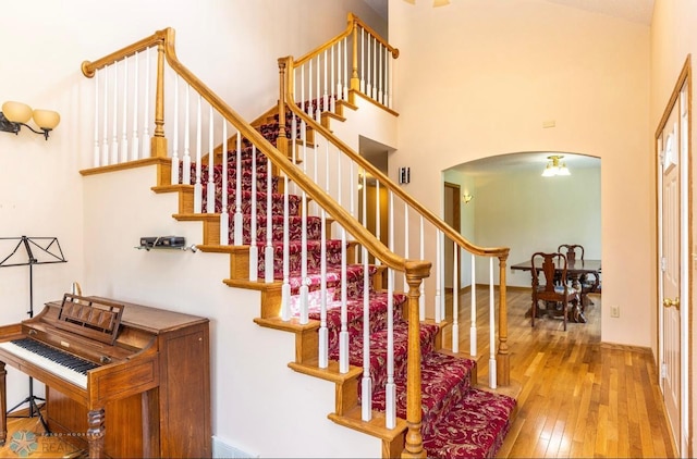 stairway with a high ceiling and wood-type flooring